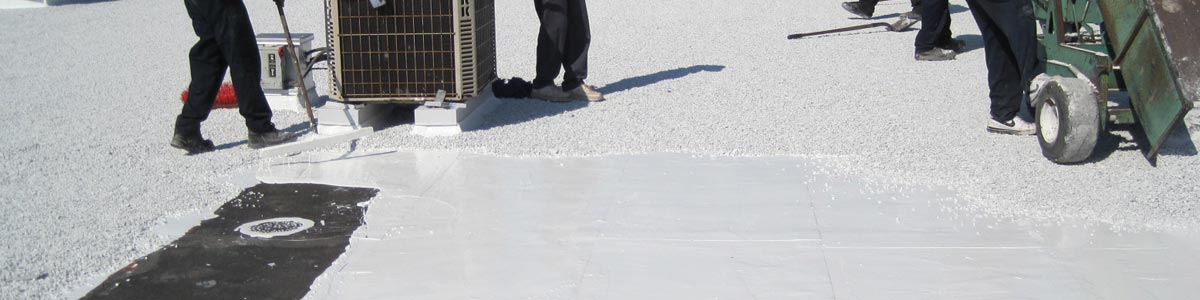 Workers apply white bonding adhesive around an air conditioning unit on a commercial roof.