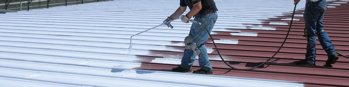 Workers apply a thin white coat of roof coating to restore a roof.