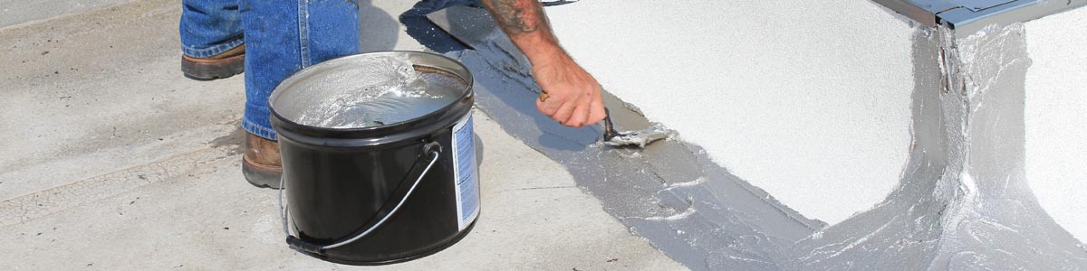 A worker applies mastic for roof repair with a trowel.